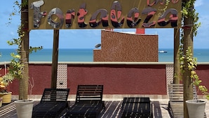 A beachside patio with a pergola, lounge chairs, and a view of the sea. - Hotel Fortaleza Inn (Fortaleza)
