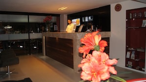 A hotel reception area with a modern design, featuring a reception desk, seating area, and a visible bar in the background. - Hotel Fortaleza Inn (Fortaleza)