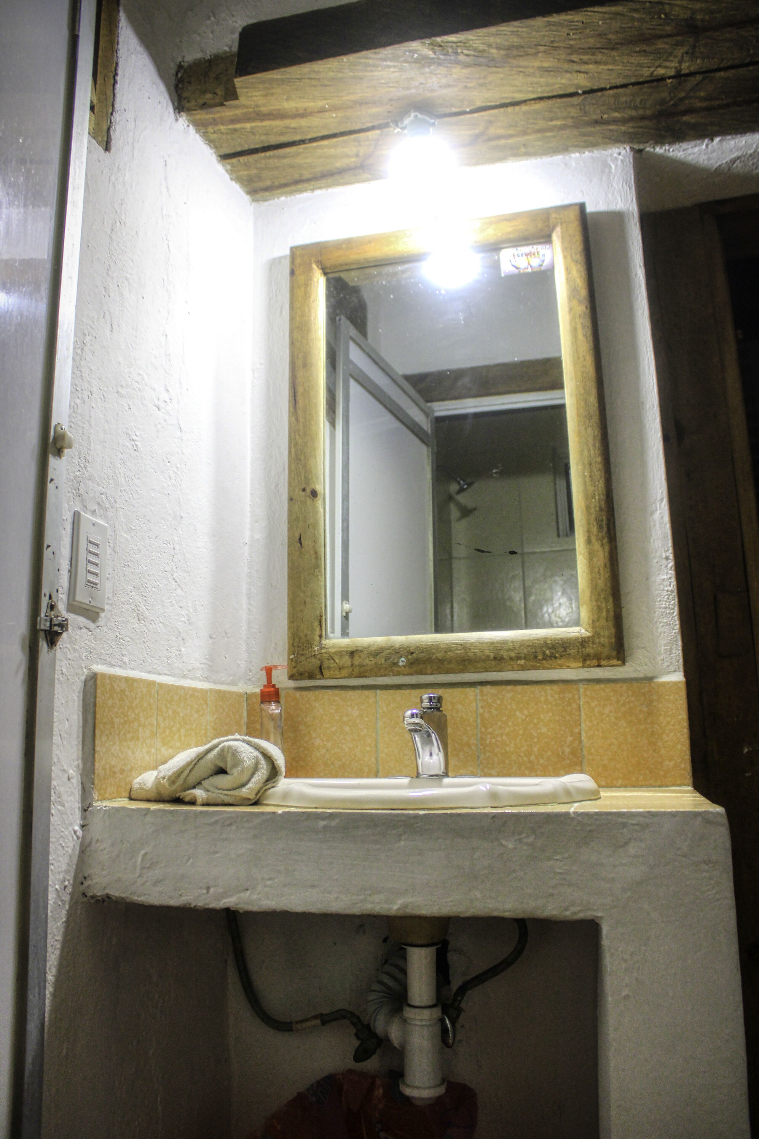 Une salle de bain avec un lavabo blanc, un miroir et une serviette accrochée au mur.