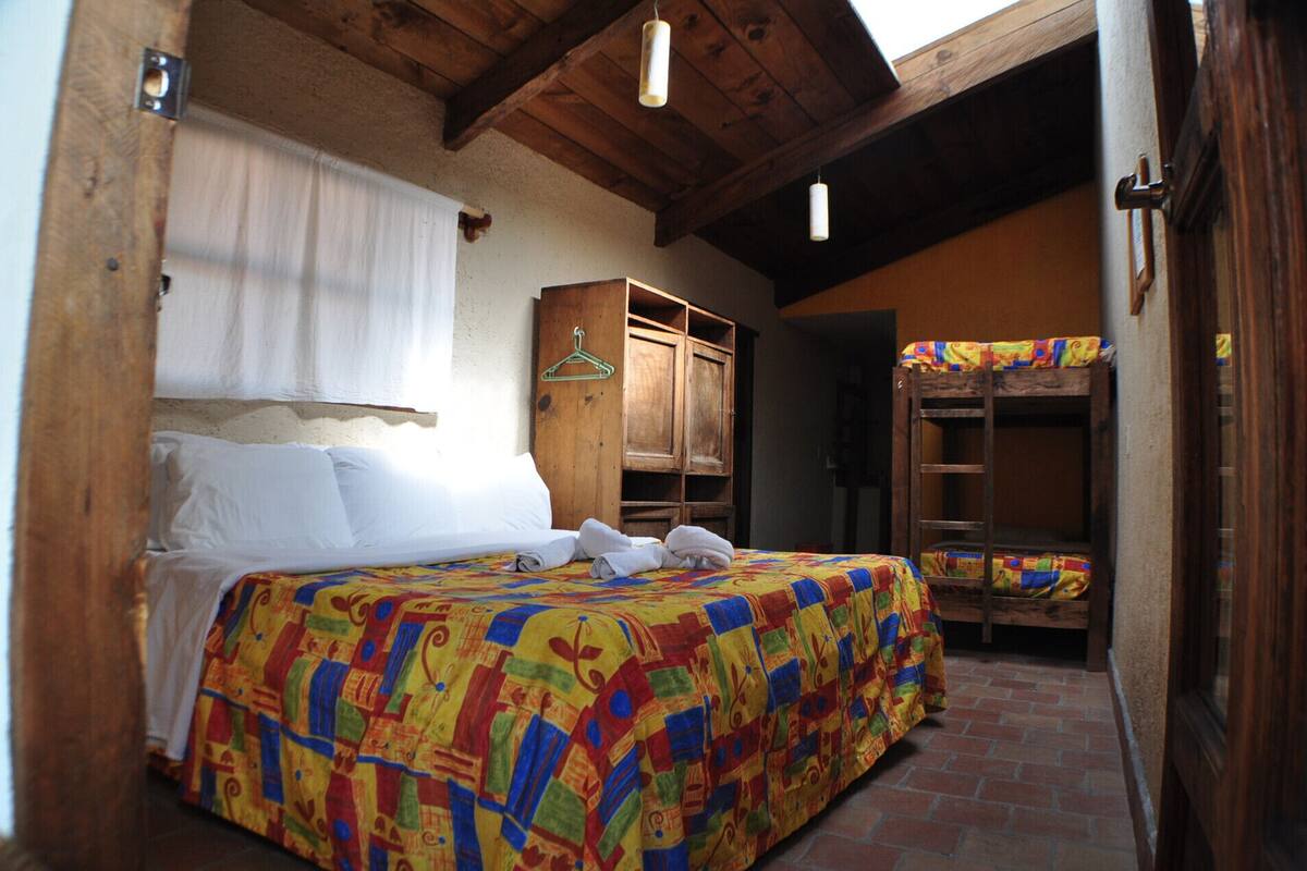 Une chambre avec un lit, une armoire en bois et un lit superposé.