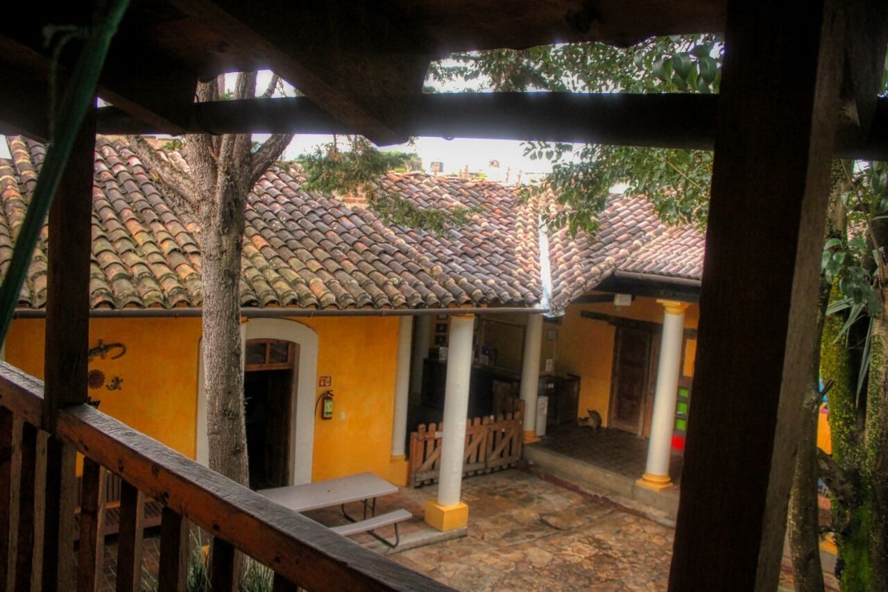A courtyard with tiled roofs, a wooden bench, and a white column.
