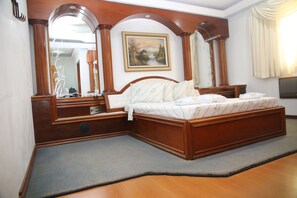 A bedroom with a wooden bed, a large mirror, and a painting on the wall. - Hotel Maison Florense (São Paulo)