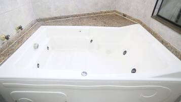 A rectangular hot tub with a control panel, set against a tiled wall with a granite countertop.