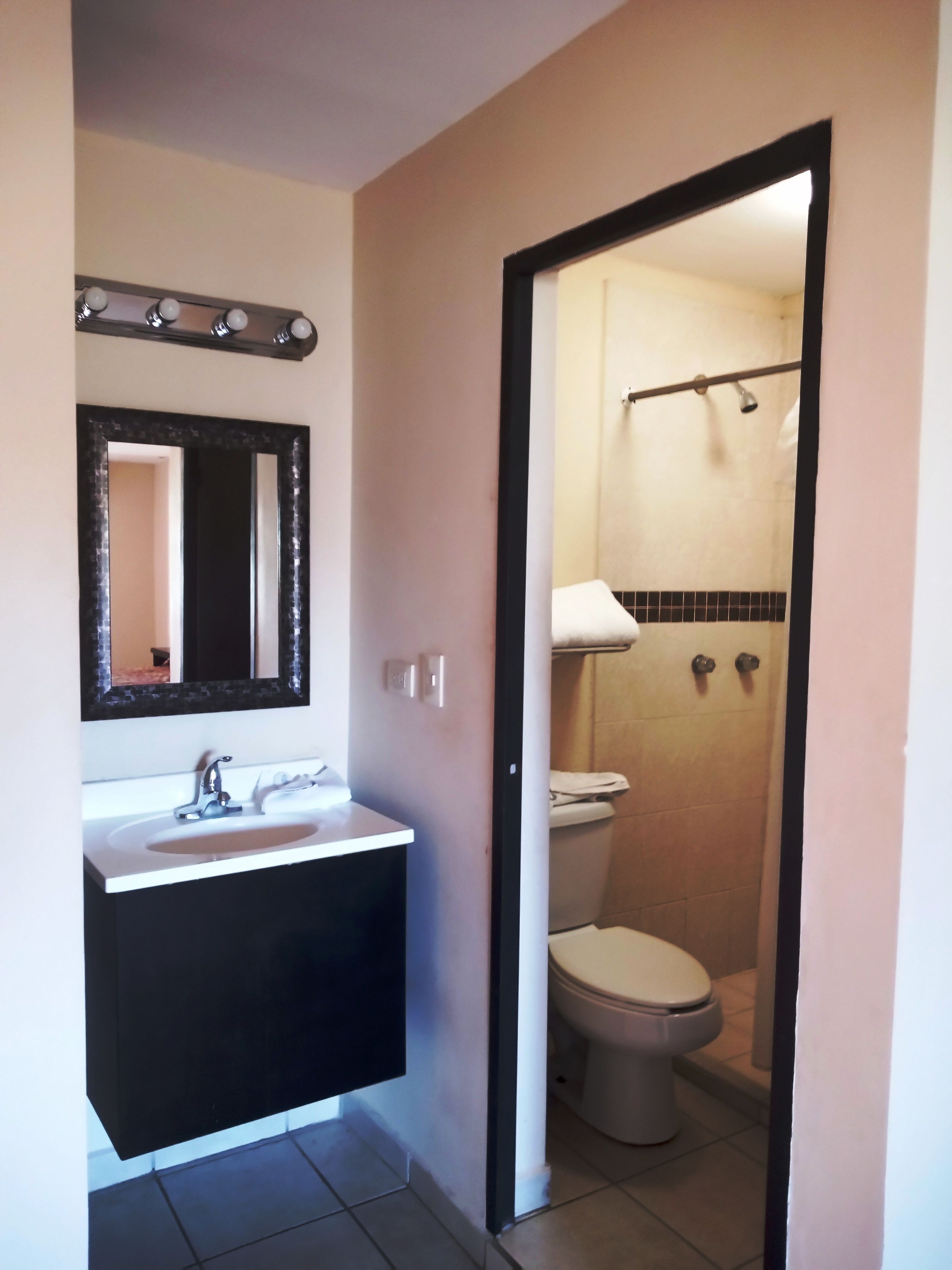 Un baño con lavamanos, espejo e inodoro.