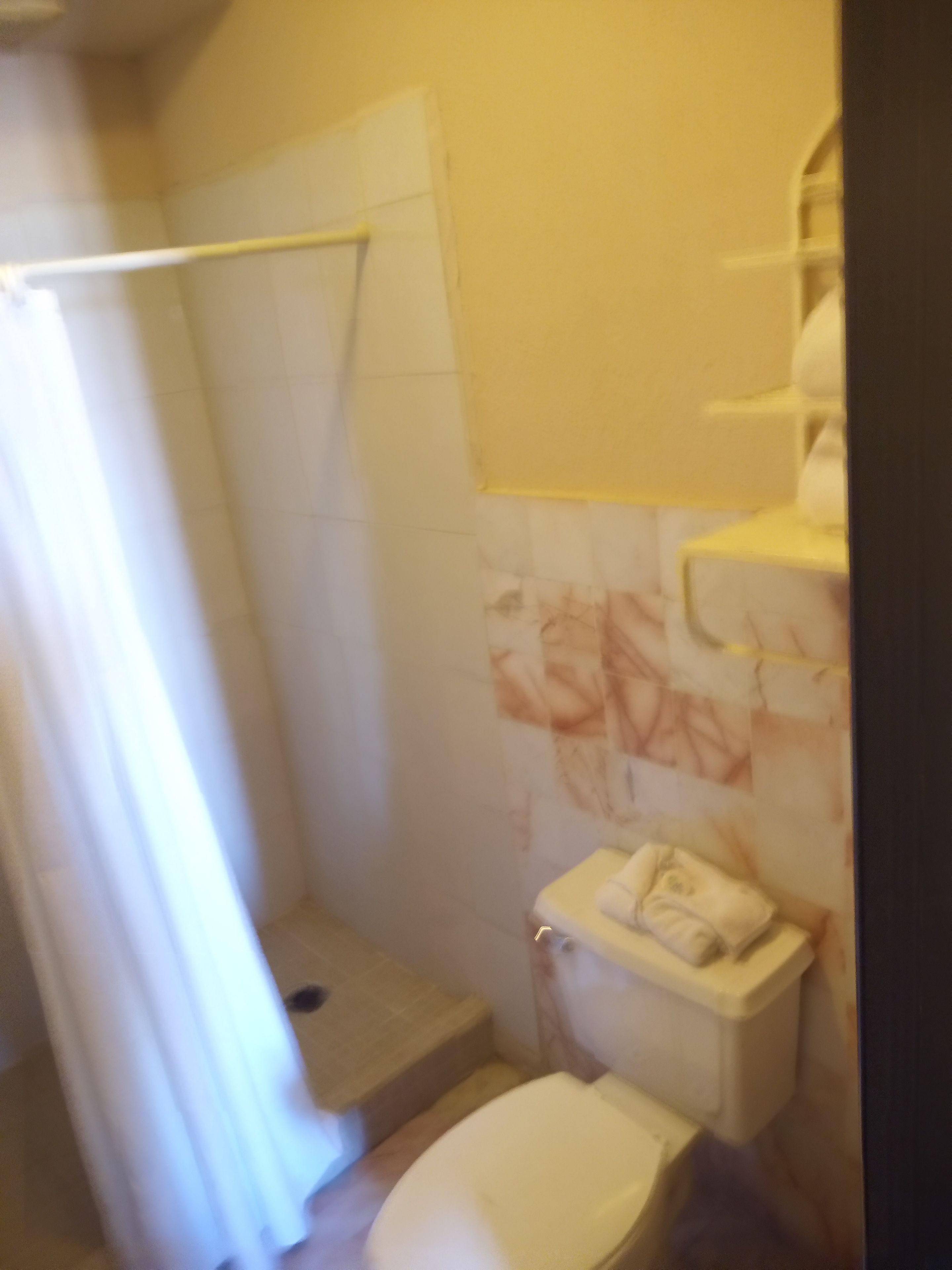 Un baño con ducha, inodoro y toallero.