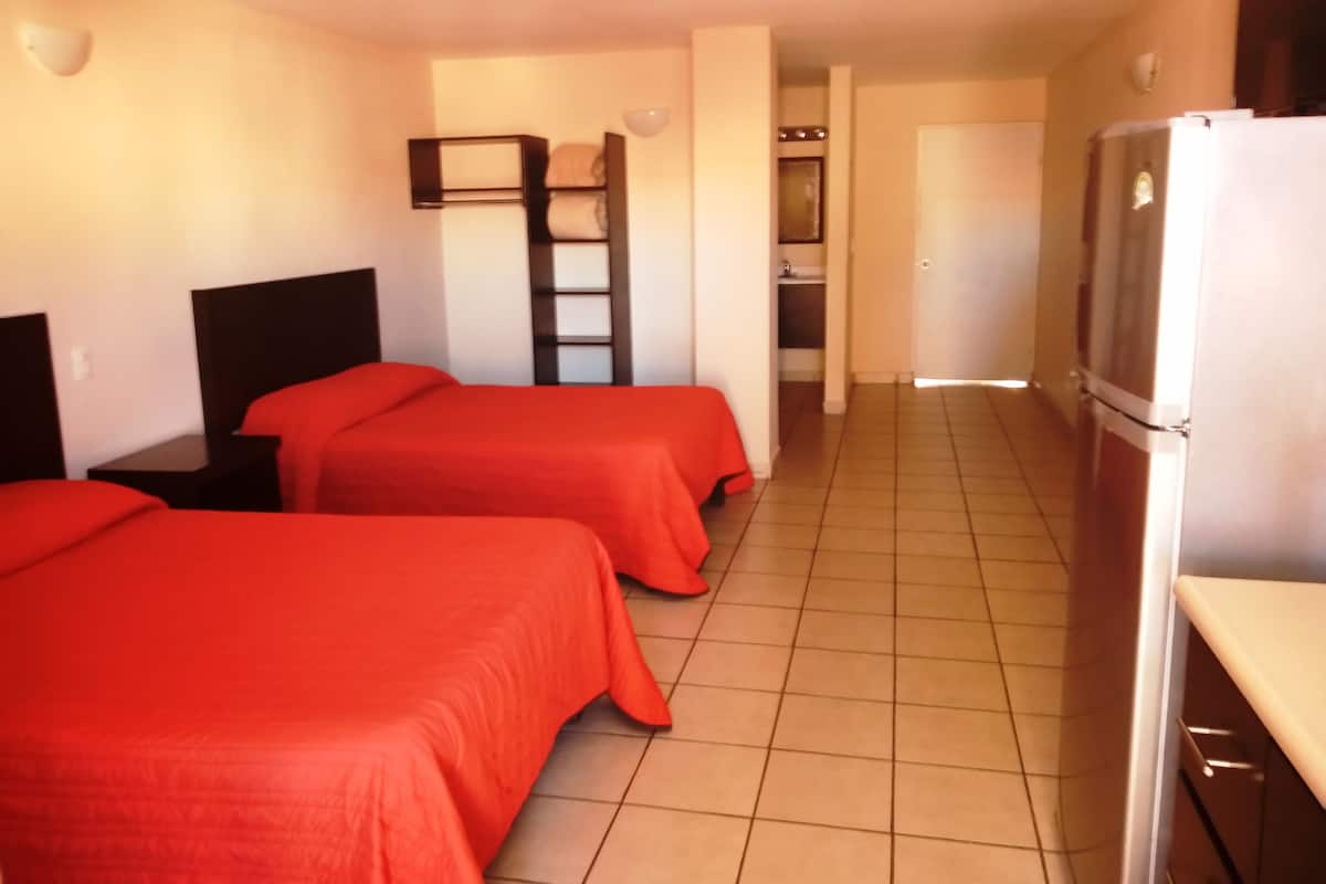 A hotel room with two beds, a refrigerator, a sink, and a small kitchenette.