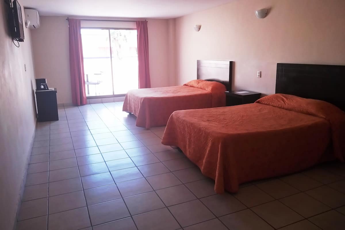 A hotel room with two beds, a desk, and a window with curtains.