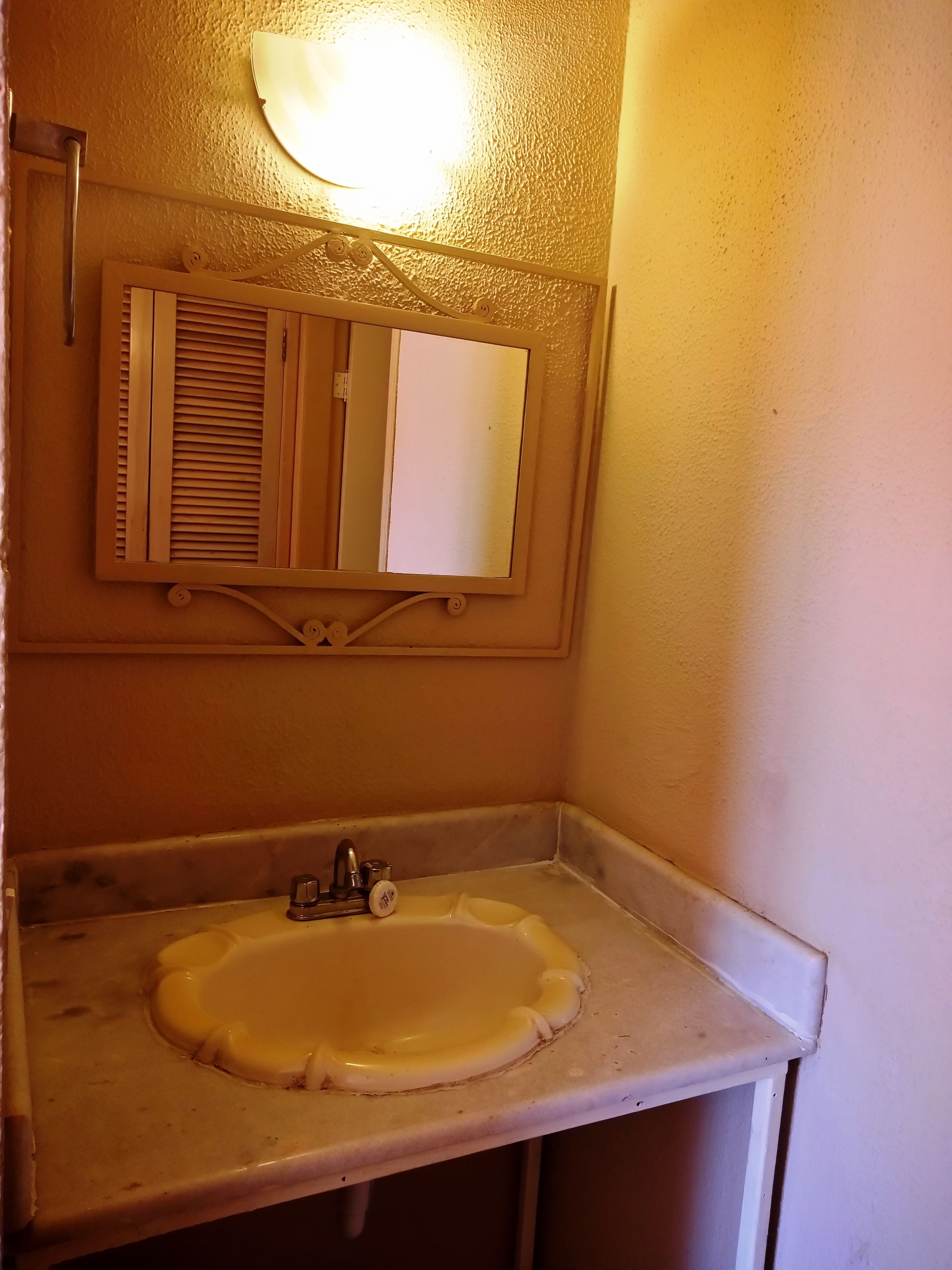 A bathroom with a white sink, a mirror, and a light fixture above the mirror.