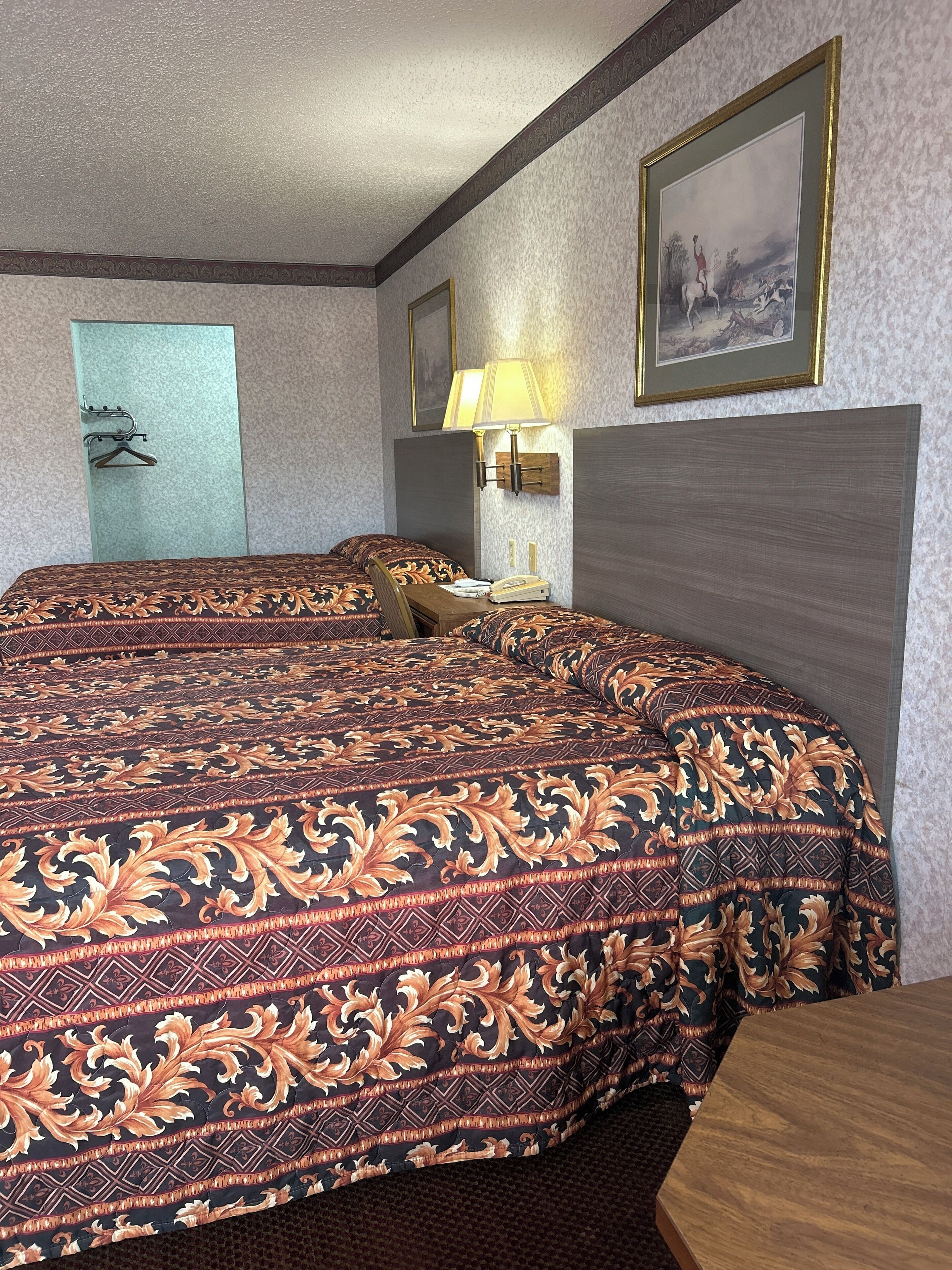Ein Hotelzimmer mit einem großen Bett, einem Nachttisch mit Lampe und einem gerahmten Bild an der Wand.
