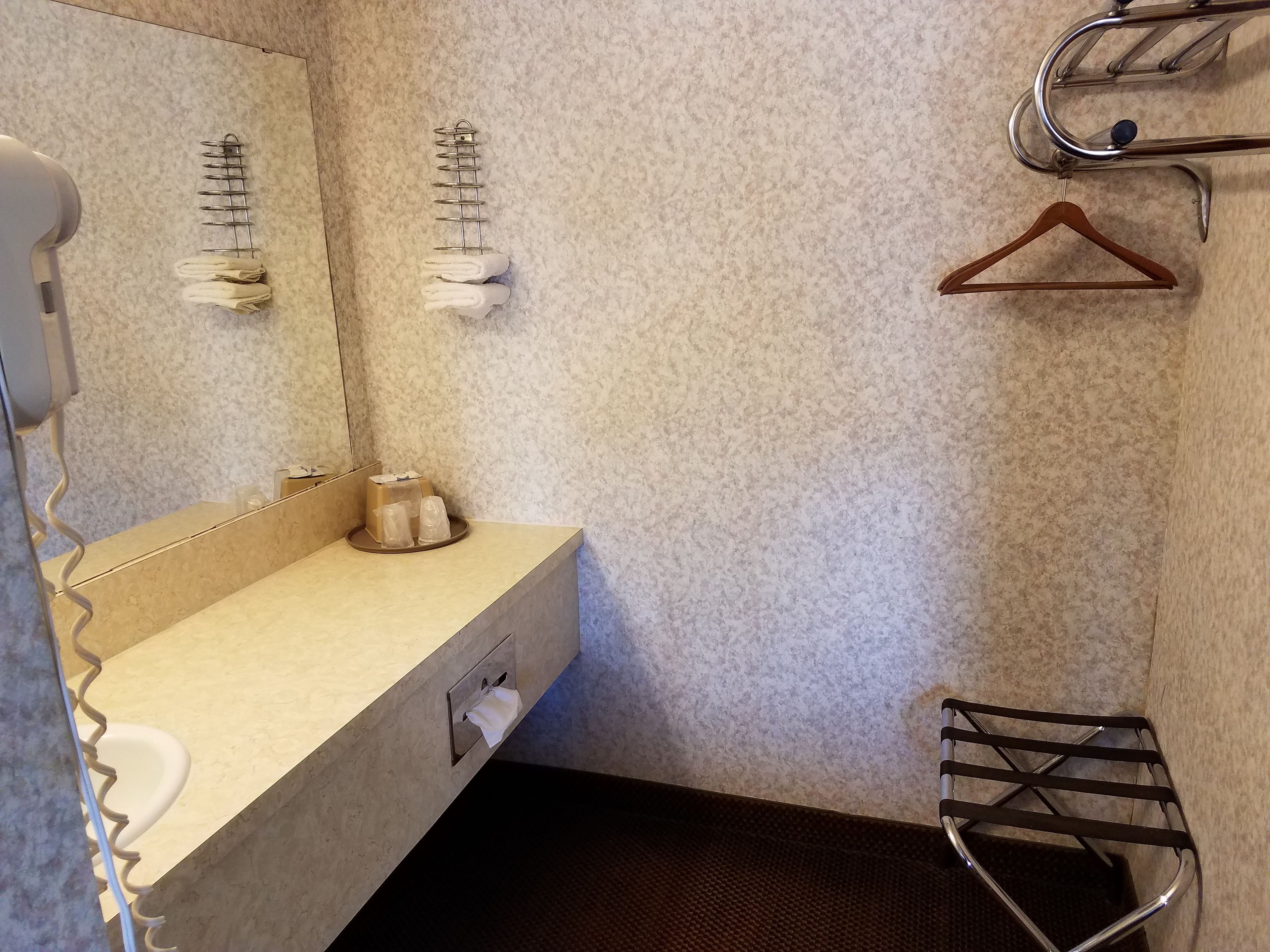 Un baño con lavamanos, espejo, toallero y una toalla colgada.