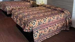 A hotel room with two beds, a nightstand with a lamp, and two framed pictures on the wall. - Heritage Inn (Duncan)