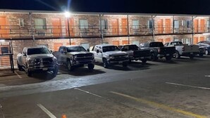 A parking lot with several vehicles, a traffic cone, and a building with orange doors in the background. - Heritage Inn (Duncan)
