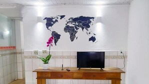 Un escritorio de madera con un televisor, una planta en maceta y un mapa del mundo en la pared.