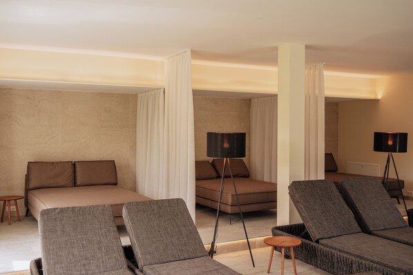 A modern hotel room with a large bed, two lounge chairs, a small table, and two floor lamps. - Schlössl Hotel Kindl (Bad Gleichenberg)