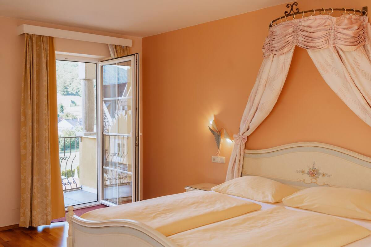 Un dormitorio con cama, cortinas y vistas al balcón.