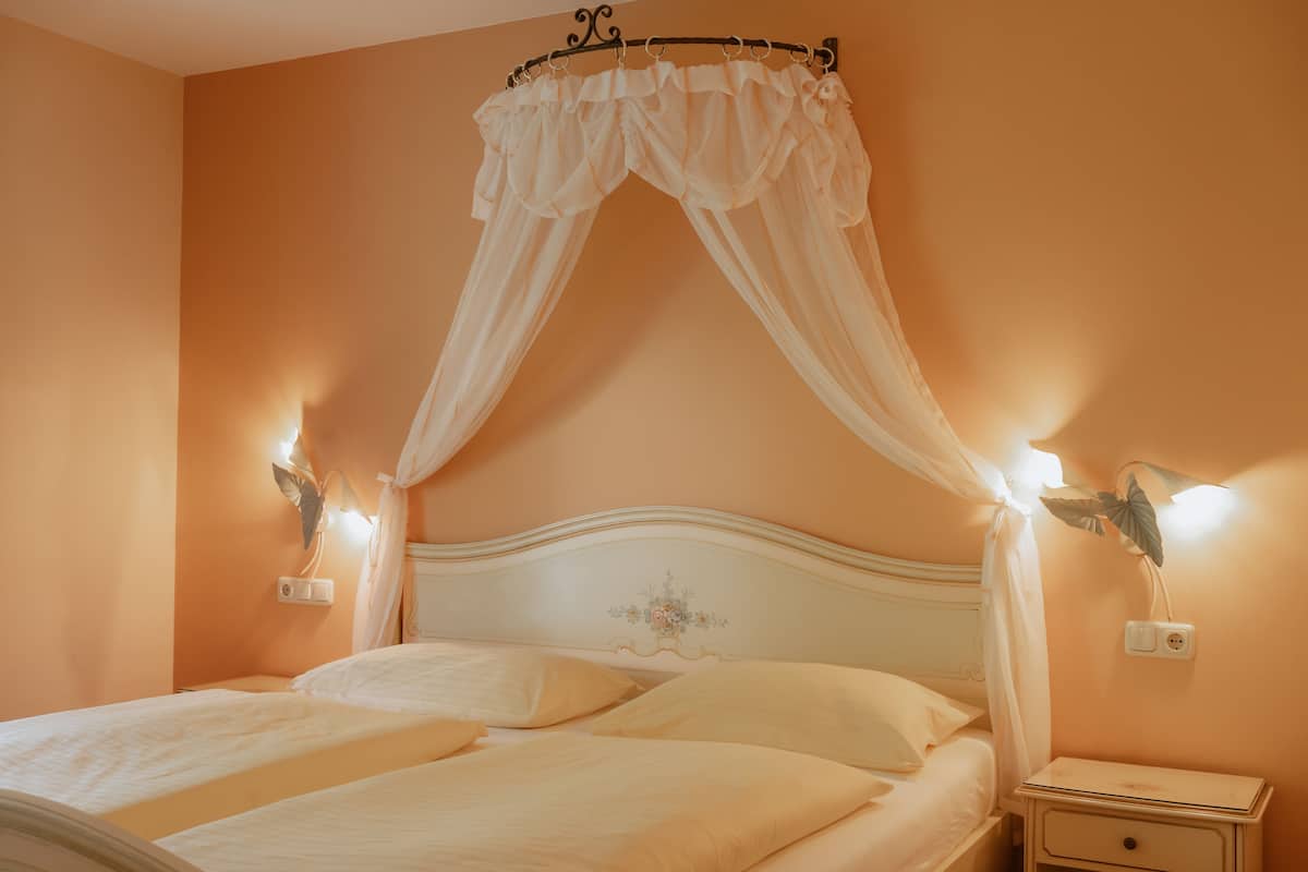 Un dormitorio con cama con dosel, lámparas de noche y mesita.