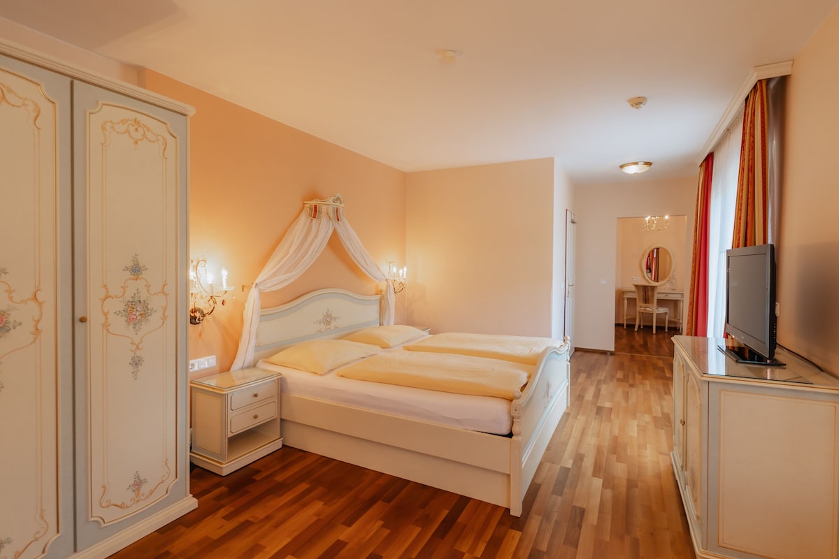 Un dormitorio con cama doble, mesitas de noche, armario y televisor.