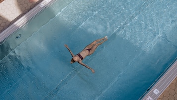 A person floating in a swimming pool with a tiled edge and a hexagonal pattern on the side.