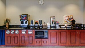 Eine Küchenzeile mit Kaffeemaschine, Mikrowelle und einer Wanduhr.