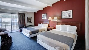 Ein Hotelzimmer mit zwei Betten, einem Sessel, einem Schreibtisch und einem Fenster mit Vorhängen.