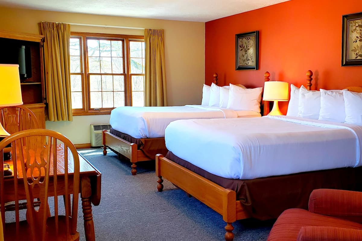 A hotel room with two beds, a desk, and a chair.