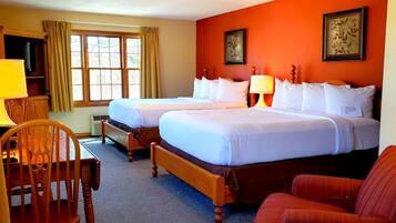 Quarto de hotel com duas camas, uma mesa e uma cadeira.