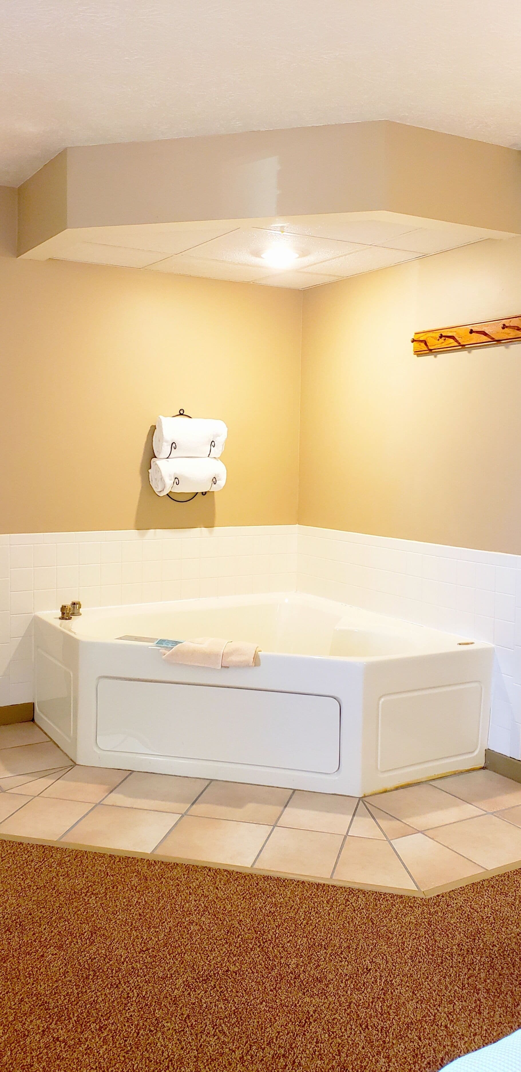 Une salle de bain avec une grande baignoire, un porte-serviettes avec des serviettes et une étagère en bois avec des crochets.