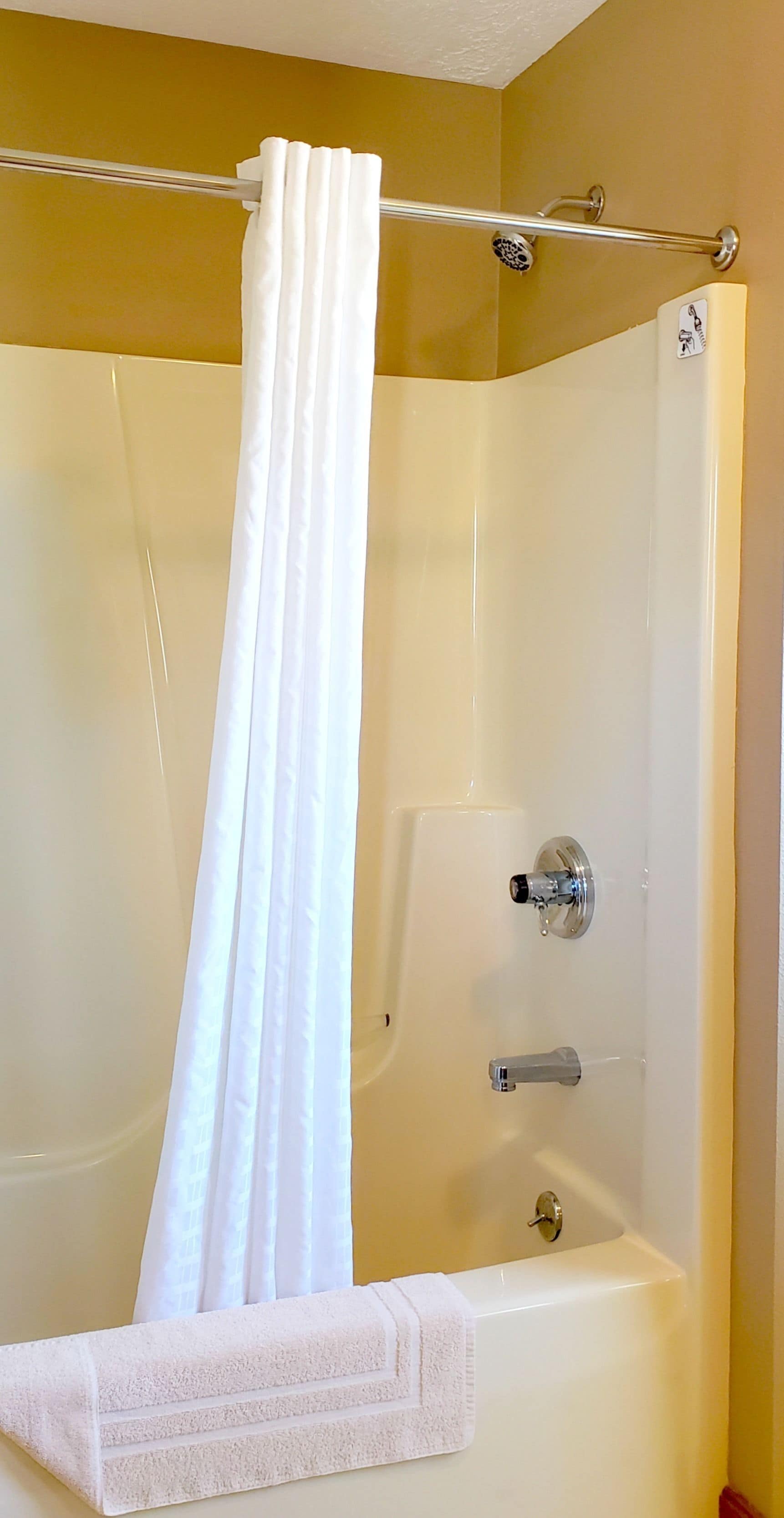 A bathtub with a shower curtain, a towel, and a control panel.