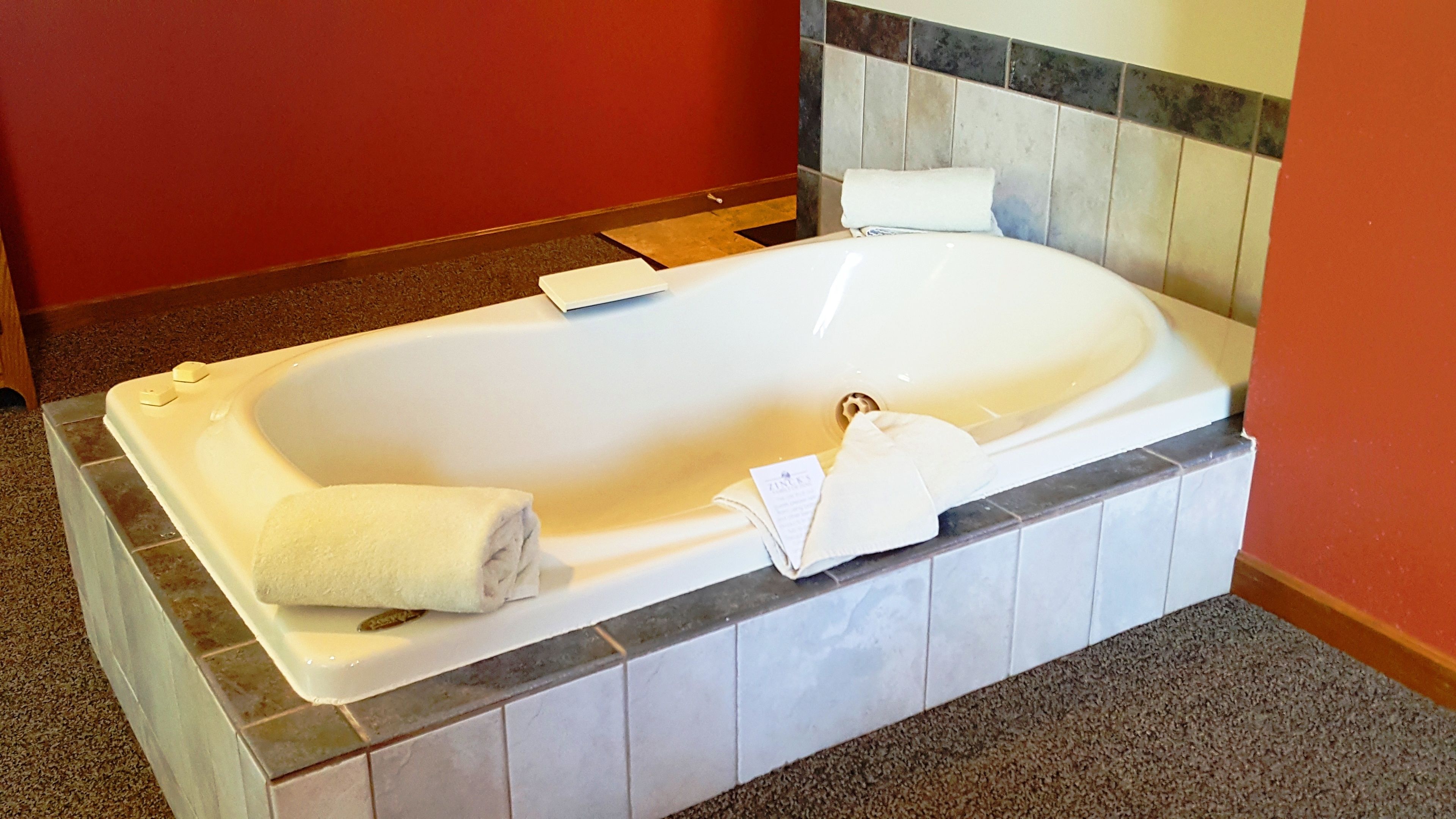 A large, rectangular, white bathtub with a single towel placed on it.