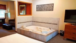 Un baño moderno con una bañera grande, un espejo, un televisor y un armario de madera.