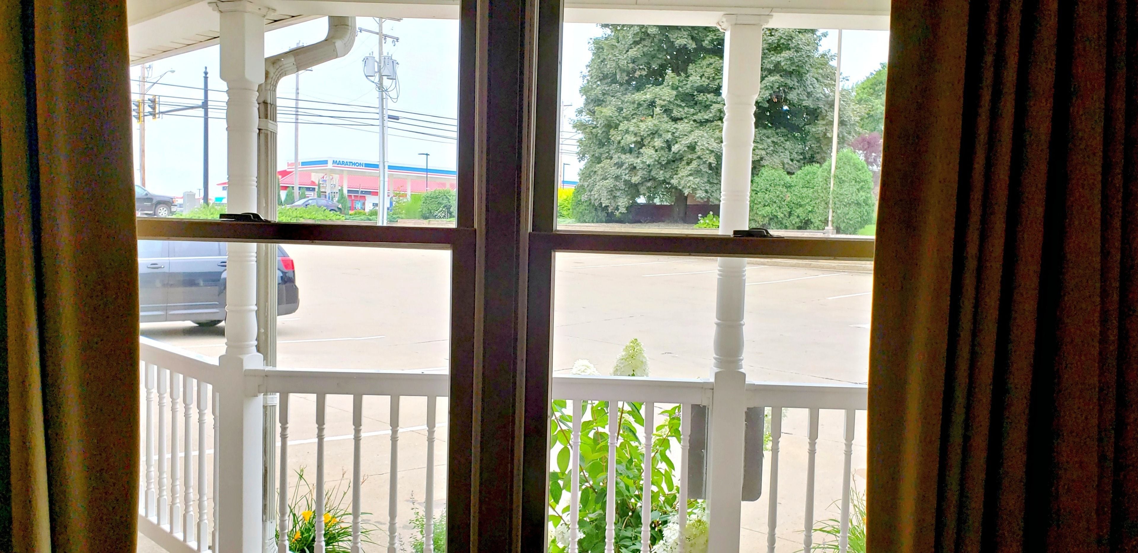 A view from a window with white railings, a street with cars, and a Marathon gas station in the background.