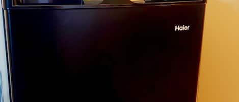 Un refrigerador Haier negro con una cafetera encima.