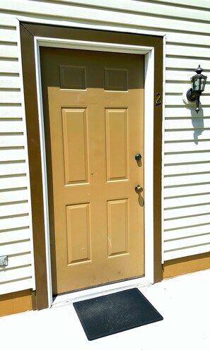 A brown front door with a doormat and a mailbox on the right.
