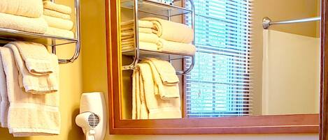A bathroom with a wooden vanity, a mirror, a towel rack, a hairdryer, and a sink.