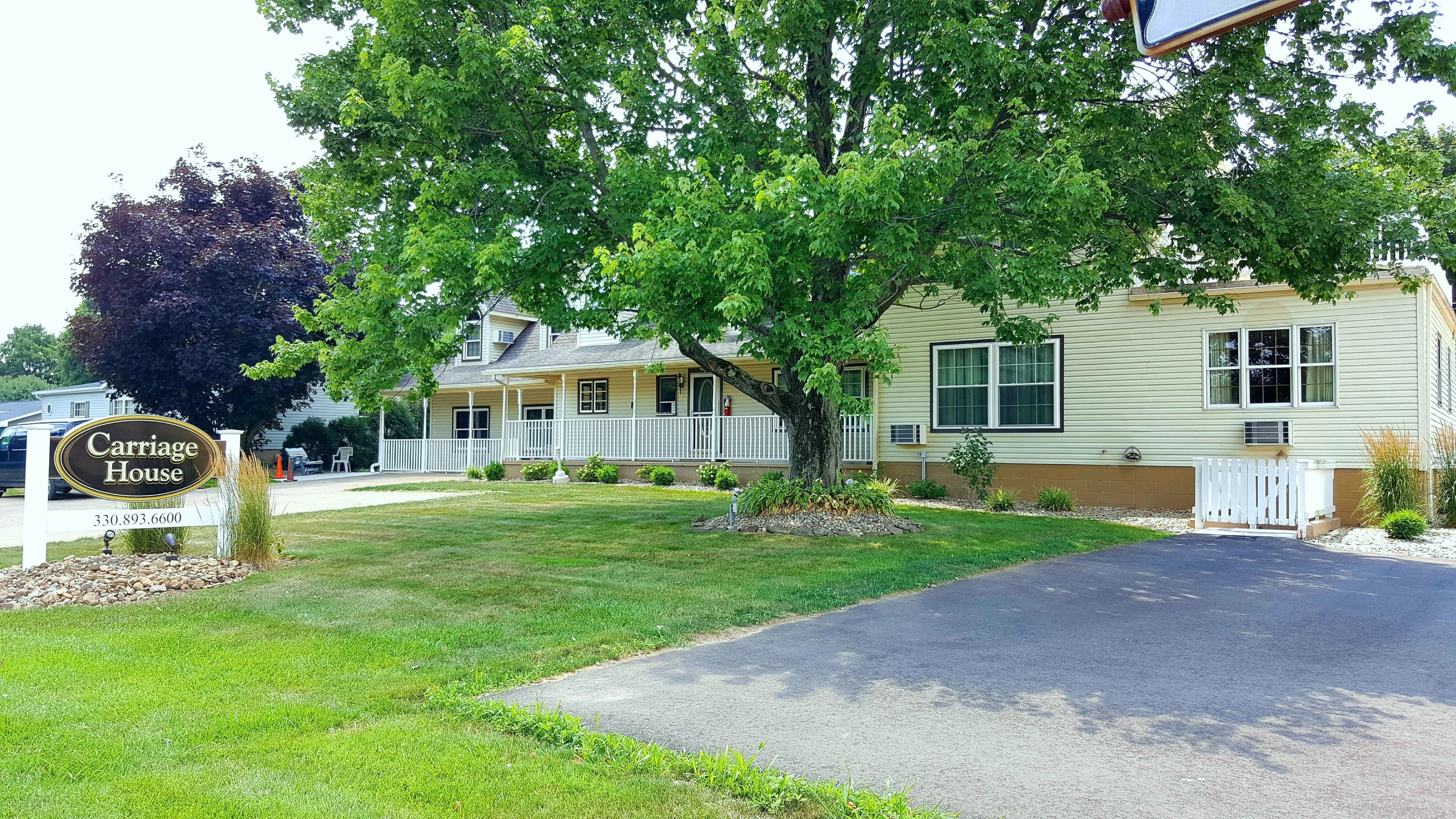 A two-story house with a porch and a sign reading "Carriage House".