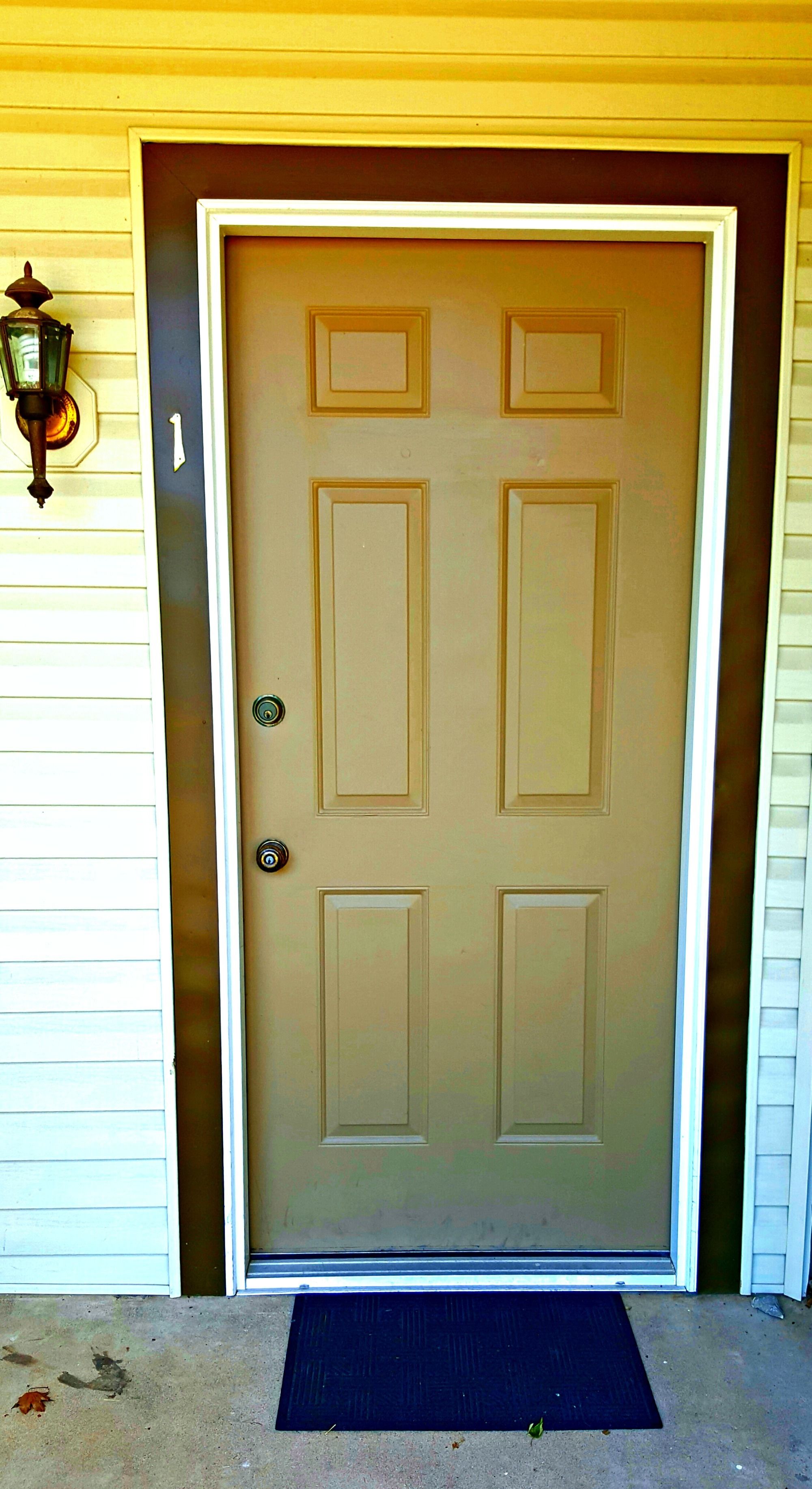 A beige double door with a doormat in front.