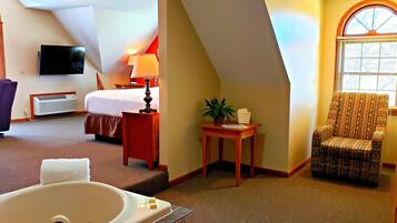Quarto de hotel com cama, escrivaninha, cadeira, televisão e janela.