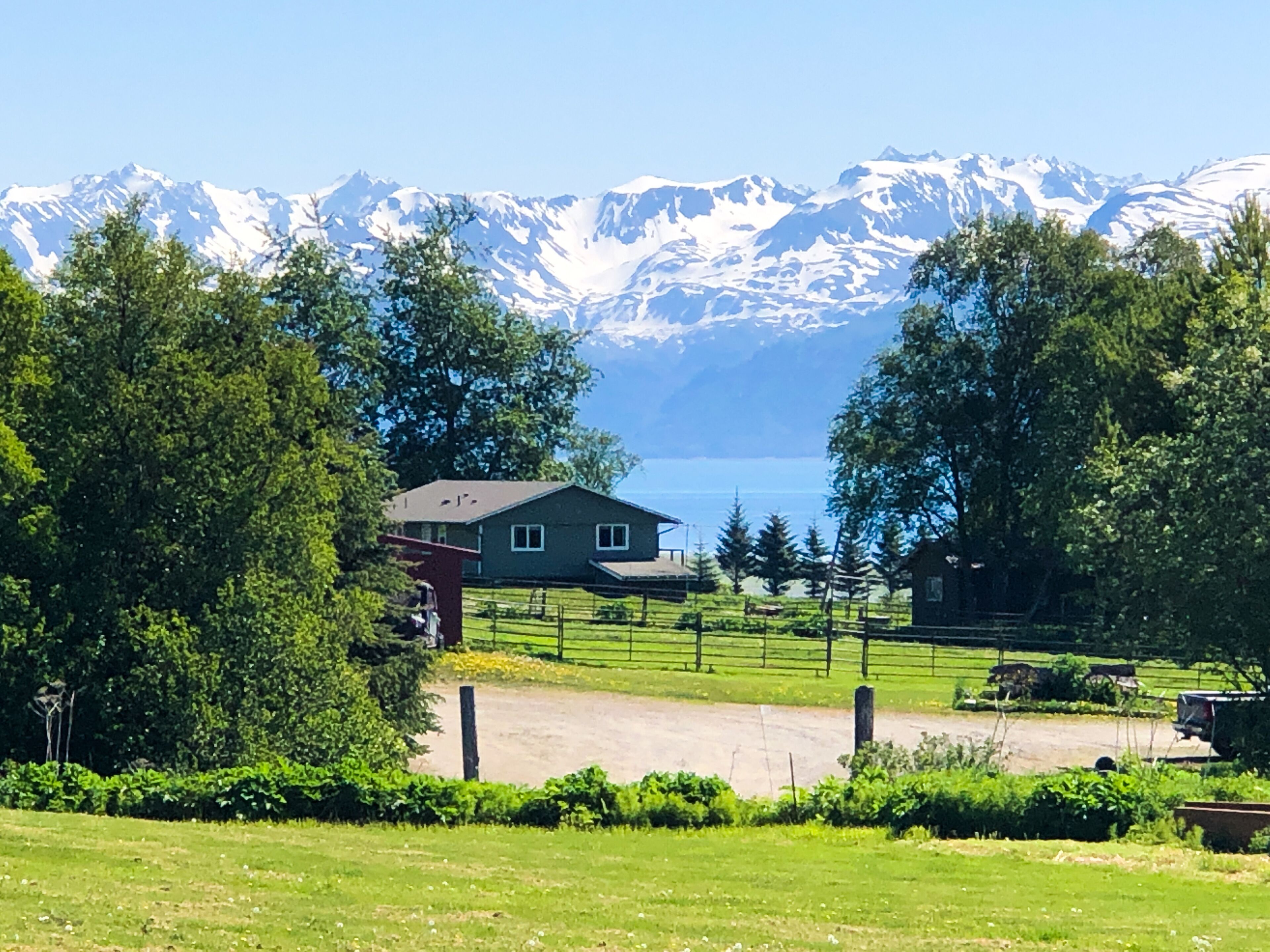 A house with a view of snow-capped mountains and a lake.