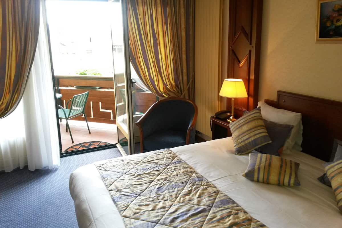 Habitación de hotel con cama, una silla, una mesa, una lámpara y vistas al exterior.