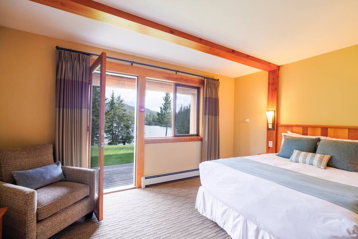 A hotel room with a bed, a chair, and a sliding glass door leading to a balcony.