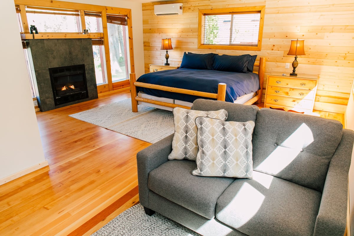 A bedroom with a bed, bedside tables, a fireplace, and a sofa.