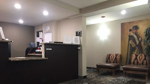 A reception area with a desk, chairs, a clock, and a painting on the wall. - Americas Best Value Inn & Suites Boise (Boise)