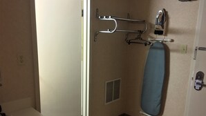 A bathroom with a shower, a towel rack, an ironing board, and a toilet. - Americas Best Value Inn & Suites Boise (Boise)