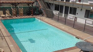 A rectangular swimming pool with a metal ladder, surrounded by a metal fence. - Days Inn by Wyndham Victorville/Hesperia I-15 & Palmdale Rd (Victorville)