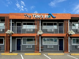Un hotel llamado "The Tide's Inn" con diseño moderno, que cuenta con varios balcones y amplias ventanas.