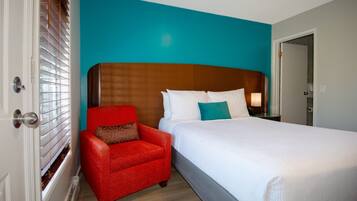 Ein Hotelzimmer mit einem großen Bett, einem roten Sessel und einer Wand in Türkis.