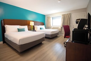 Habitación de hotel con dos camas, un escritorio, una silla y un televisor.