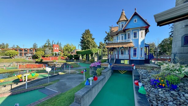 Un edificio azul con una torre, rodeado de un campo de mini golf.