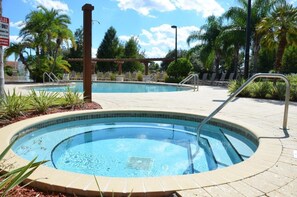 A pool area with two hot tubs, surrounded by palm trees and lounge chairs. - Lucaya Village by VHC Hospitality (Kissimmee)