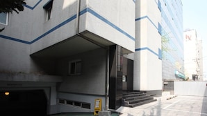 A modern building with a unique architectural design, featuring a large overhang and a staircase leading to an entrance. - Prince Hotel (Seoul)